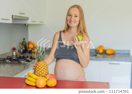 Embracing a healthy choice, a pregnant woman prepares to enjoy a nutritious moment, gearing up to eat fresh fruit and nourish herself during her pregnancy 111714701
