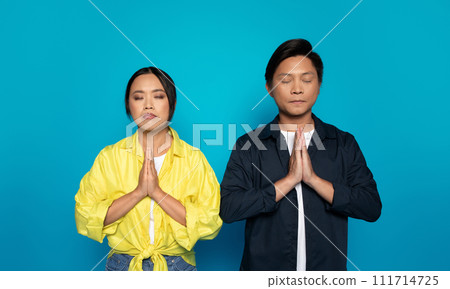 Serious pensive asian man and lady in casual with closed eyes pray, dream, make wish come true 111714725