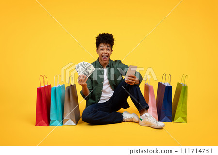 Happy young black guy with smartphone and cash in hands Happy young black guy with smartphone and cash in hands 111714731