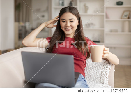 Domestic Leisure. Young Asian Woman Relaxing With Coffee And Laptop At Home Domestic Leisure. Young Asian Woman Relaxing With Coffee And Laptop At Home 111714751