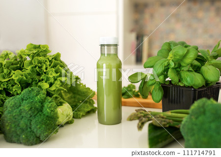 Bottle of nutritious green smoothie standing on table amidst herbs 111714791