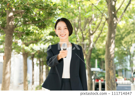 Female announcer with microphone outdoors 111714847