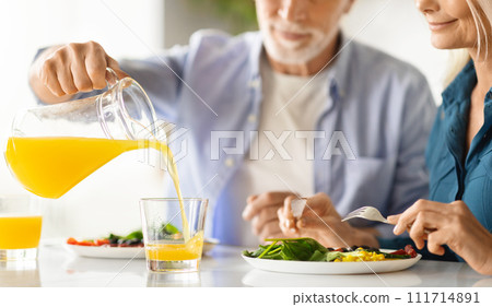 Elderly spouses having breakfast together in kitchen, cropped shot 111714891