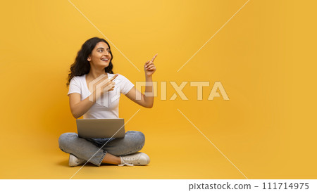 Smiling young indian woman using laptop sitting on floor Smiling young indian woman using laptop sitting on floor 111714975