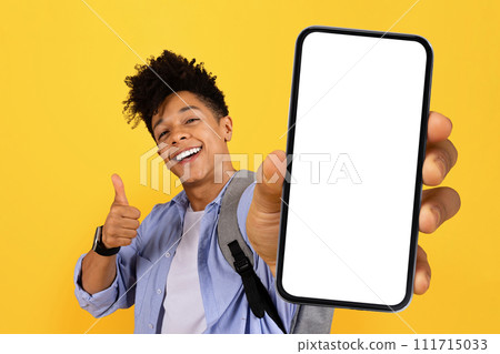 Cheerful black guy student showing phone screen and gesturing thumb up Cheerful black guy student showing phone screen and gesturing thumb up 111715033