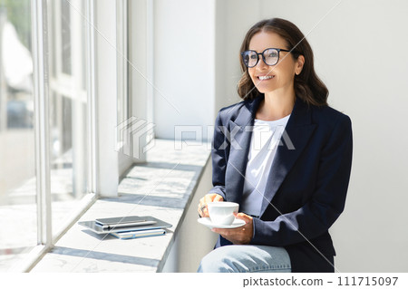 Positive middle aged european businesswoman with phone, drink coffee Positive middle aged european businesswoman with phone, drink coffee 111715097