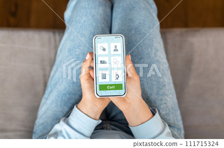 Female at home exploring telemedicine options on healthcare app using her smartphone Female at home exploring telemedicine options on healthcare app using her smartphone 111715324