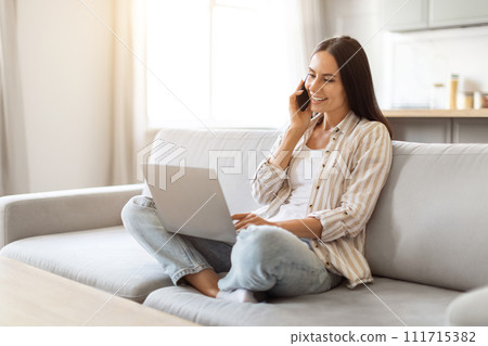Remote Career. Smiling Woman Talking On Cellphone And Using Laptop At Home Remote Career. Smiling Woman Talking On Cellphone And Using Laptop At Home 111715382