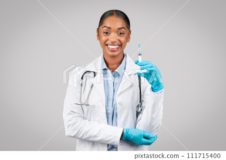 Happy pretty young black lady doctor in white coat show syringe, recommends injection, health care Happy pretty young black lady doctor in white coat show syringe, recommends injection, health care 111715400