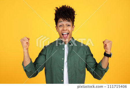 Thrilled young african american guy clenching fists on yellow Thrilled young african american guy clenching fists on yellow 111715406