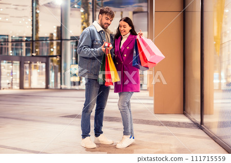 Man hands over present box to girlfriend at mall outdoor 111715559