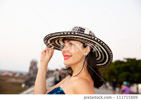 Beautiful woman wearing the traditional Colombian hat called Sombrero Vueltiao at the historical streets of the Cartagena de Indias walled city 111715809