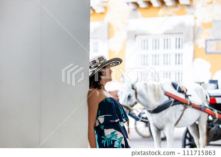 Beautiful woman wearing the traditional Colombian hat called Sombrero Vueltiao at the Customs Square on the historical streets of the Cartagena de Indias walled city Beautiful woman wearing the traditional Colombian hat called Sombrero Vueltiao at the Customs Square on the historical streets of the Cartagena de Indias walled city 111715863