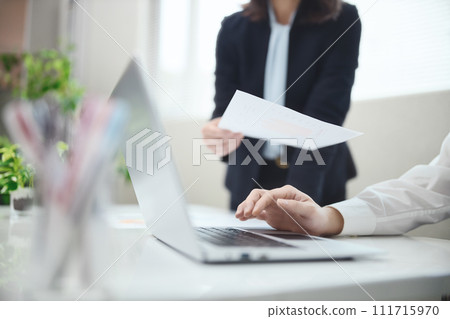 Hands of a businessman operating a computer while having a meeting in the office 111715970