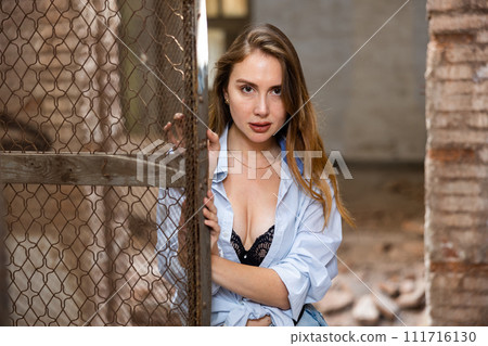 Woman in shirt tied in knot and black lace bra posing in abandoned house 111716130