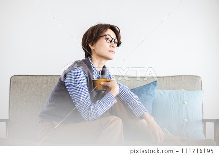 A woman drinking coffee on the sofa A woman drinking coffee on the sofa 111716195