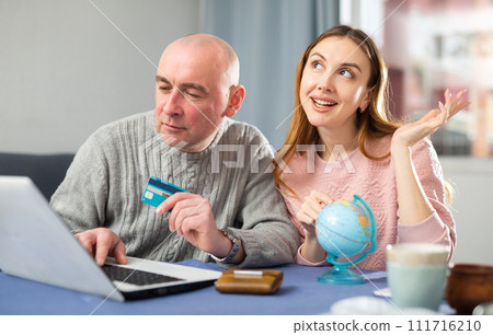 Happy married couple book a vacation tour on a laptop Happy married couple book a vacation tour on a laptop 111716210