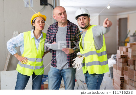 Homeowner discussing home renovation work plan with builders 111716228