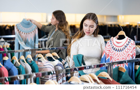 Portrait of woman holding winter sweater in store 111716454