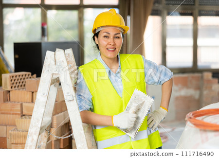 Female builder posing on indoor construction site 111716490