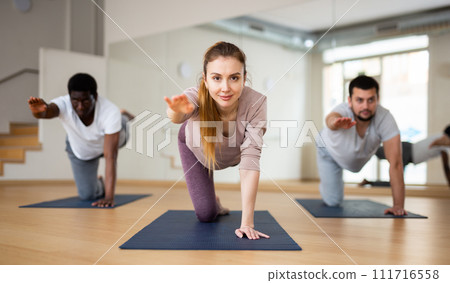 Woman practicing Dandayamna Bharmanasana during group yoga training Woman practicing Dandayamna Bharmanasana during group yoga training 111716558