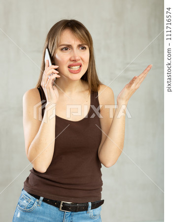 Young woman argues over phone with fury, anger and frustration 111716574