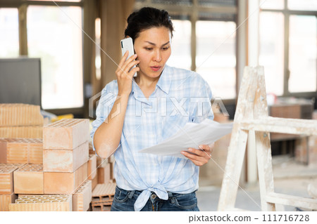 Woman talking on phone at renovating object 111716728