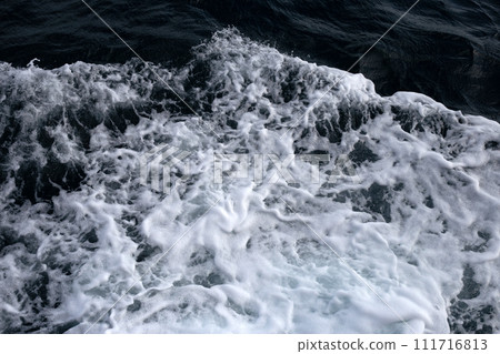 Blue sea waves and white foam from the side of the ship. 111716813