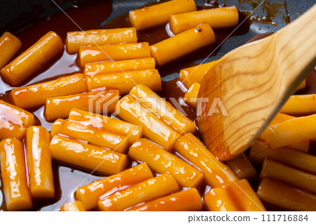 在煎鍋裡製作甜辣辣的炒年糕的烹飪場景。 在煎鍋裡製作甜辣辣的炒年糕的烹飪場景。 111716884