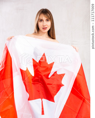 Confident young woman with national flag of Canada looking at camera at gray wall background 111717009
