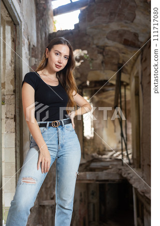 Young woman in jeans and black t-shirt posing inside ruined house 111717080