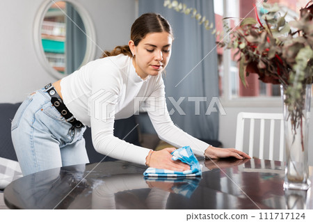 Young woman cleaning table in living room Young woman cleaning table in living room 111717124