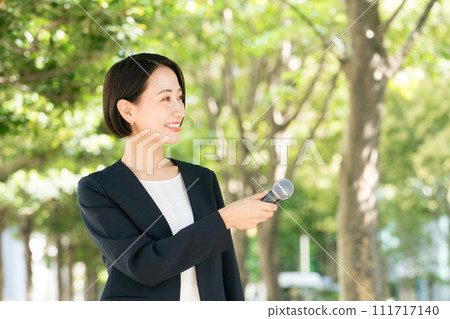 Female announcer with microphone outdoors 111717140
