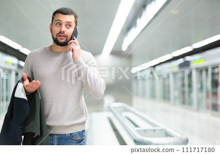Man with luggage talking on mobile phone at the station in subway 111717180