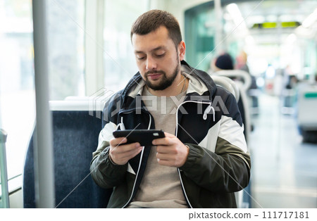 Male passenger in casual clothing talking on mobile phone in tram 111717181