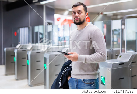 Male passenger in casual clothing near baffle gate in underground platform closeup Male passenger in casual clothing near baffle gate in underground platform closeup 111717182
