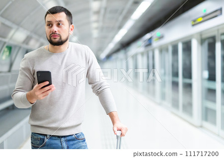 Young man browsing messages on phone at subway station Young man browsing messages on phone at subway station 111717200