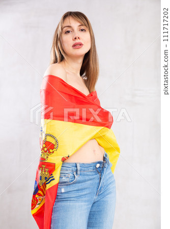 Semi-nude young woman wrapped in flag of Spain posing in studio Semi-nude young woman wrapped in flag of Spain posing in studio 111717202