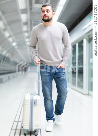 Young man walking through metro station with suitcase 111717203