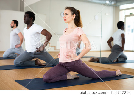 Woman doing stretching exercises during group yoga class Woman doing stretching exercises during group yoga class 111717204