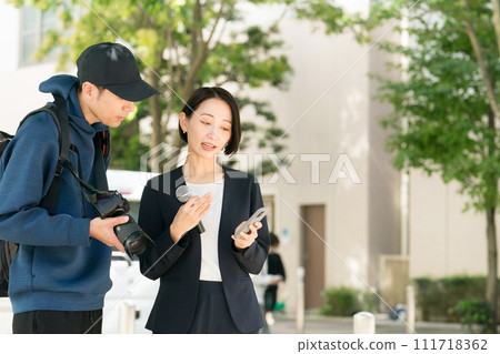 Reporter and cameraman reporting outdoors 111718362