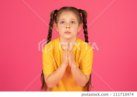 Cute preteen girl in yellow tshirt making please gesture with clasped hands Cute preteen girl in yellow tshirt making please gesture with clasped hands 111718474