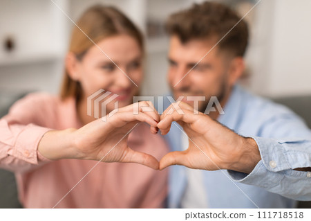 Young couple forms heart shape with fingers symbolizing love indoor Young couple forms heart shape with fingers symbolizing love indoor 111718518