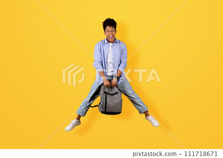 Happy black man mid-jump holding backpack 111718671