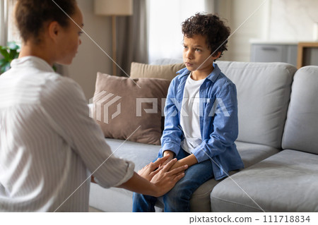 Black mother and son in serious conversation on sofa at home 111718834