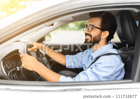 Cheerful eastern young man in casual manager driving white car Cheerful eastern young man in casual manager driving white car 111718877