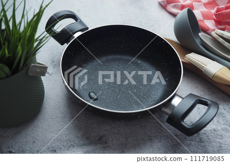empty frying pan and kitchen spoon on table  111719085