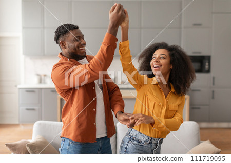 Cheerful millennial black spouses having fun together dancing in kitchen Cheerful millennial black spouses having fun together dancing in kitchen 111719095