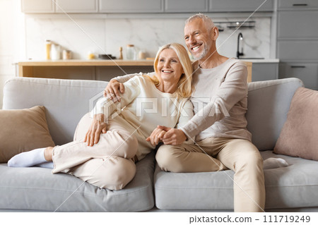 Beautiful elderly caucasian couple cuddling on couch at home 111719249