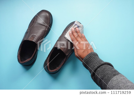 Men wipes his leather shoes with a wet cloth 111719259